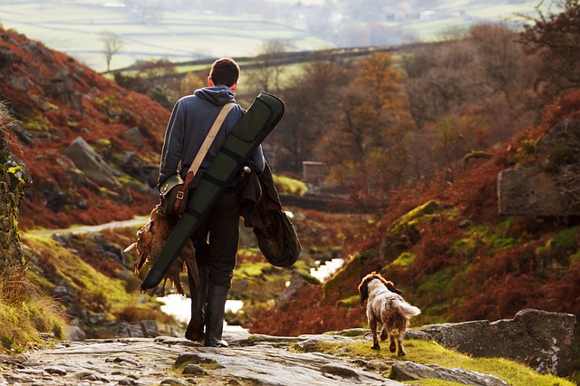 Un chasseur et son chien, de dos, rentrant de la chasse son gibier à la main