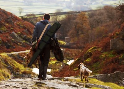 Un chasseur et son chien, de dos, rentrant de la chasse son gibier à la main