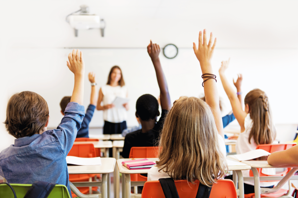 Elèves en classe qui lèvent la main